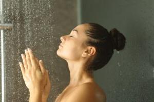 Woman holding her hands under the warm shower water